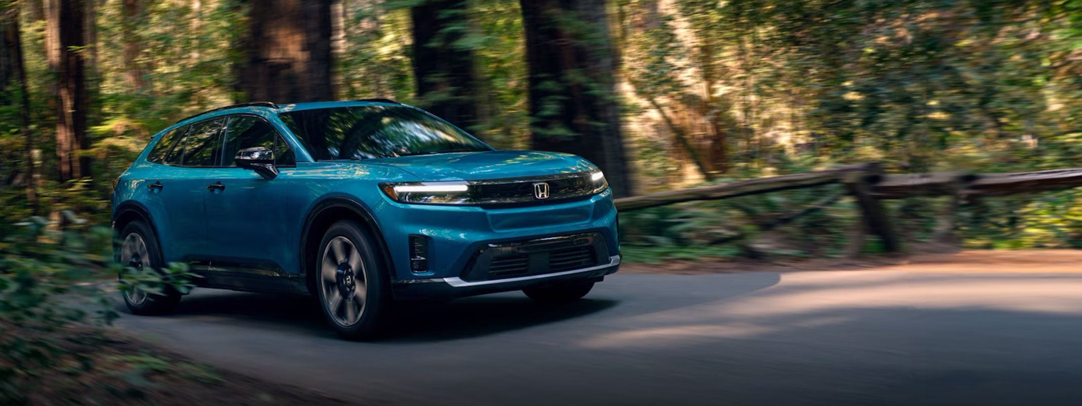 Blue Honda SUV driving in woods